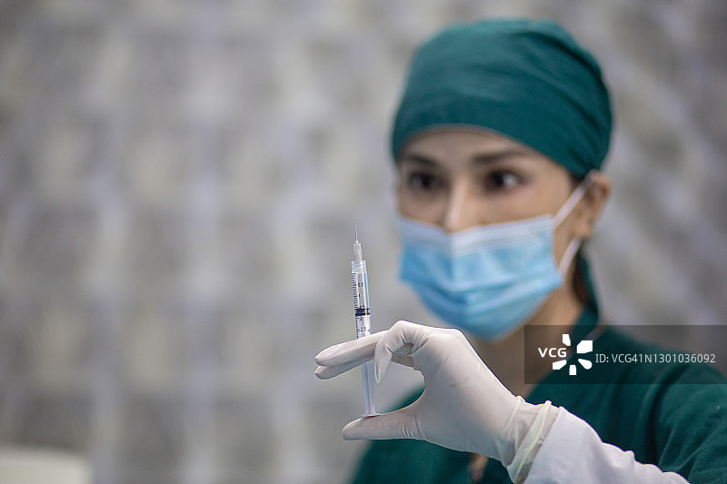 戴着口罩、准备注射新冠疫苗的亚洲女医生图片素材