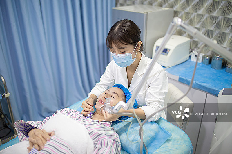 中国女性在医疗中心接受激光面部治疗，皮肤年轻化概念图片素材