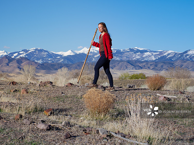 在山区背景下拄着拐杖徒步的女人图片素材