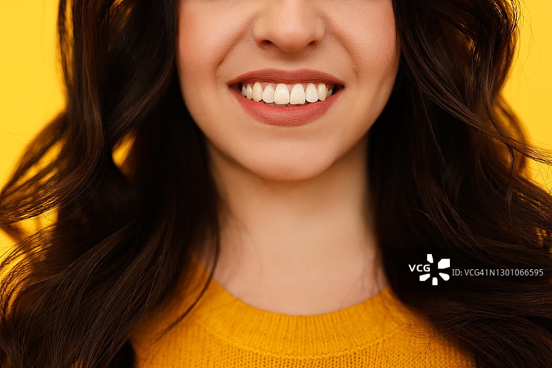 黄背景上棕色头发女孩快乐笑容的特写。牙科医院广告图片素材