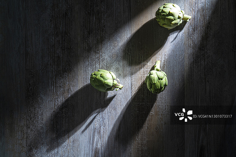 灰色木桌上的三个洋蓟图片素材