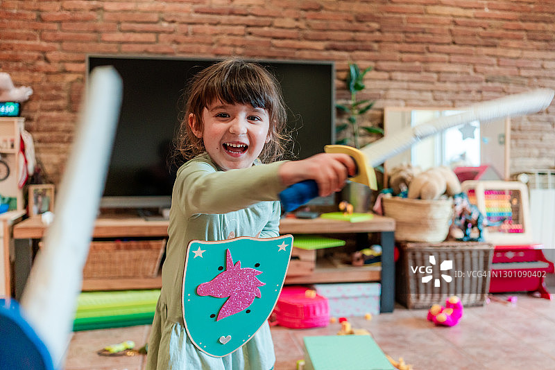 4岁小女孩玩公主游戏，挥舞剑和盾牌图片素材