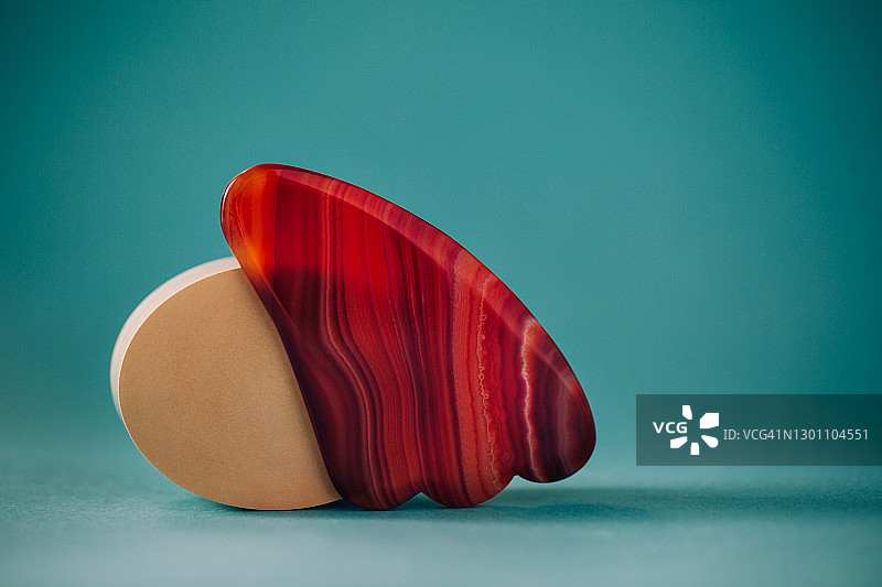 肉色背景上带玛瑙的刮痧板面部按摩器，具有健康概念图片素材