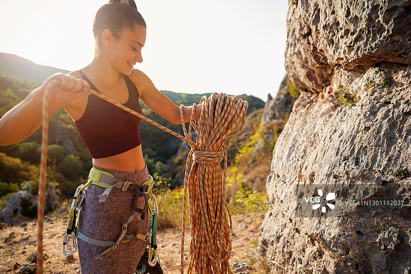 准备攀岩绳的微笑女性攀岩者的侧视图图片素材