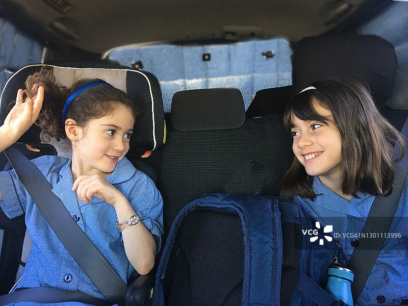 上学途中坐在汽车座椅上互相看着的姐妹图片素材