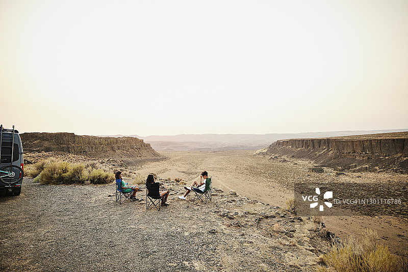 一家人在夏季房车旅行期间在沙漠峡谷附近的露营椅上放松图片素材