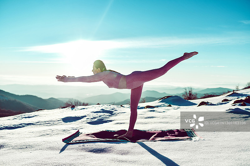 女性瑜伽专家在雪地中展示战士三式瑜伽图片素材