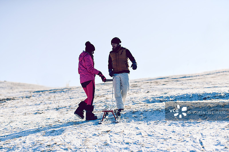 情侣在山区雪地里一起玩雪橇图片素材