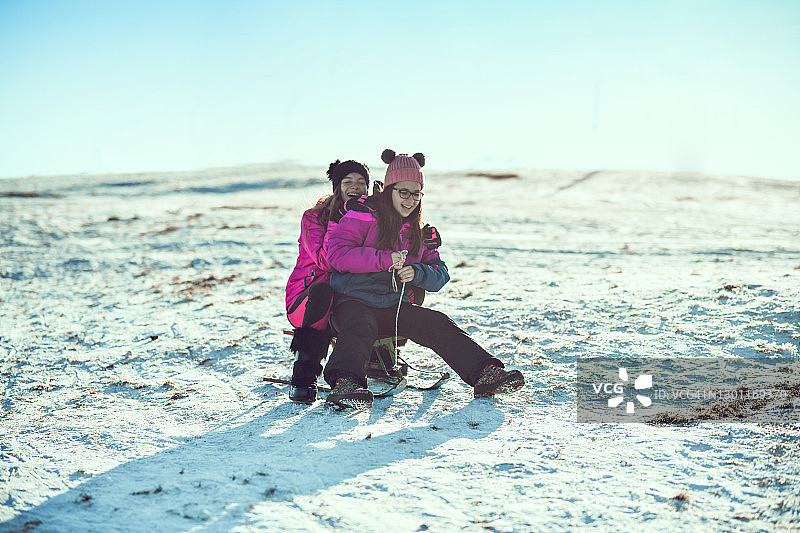 在雪山上乘坐雪橇滑下来的女孩图片素材