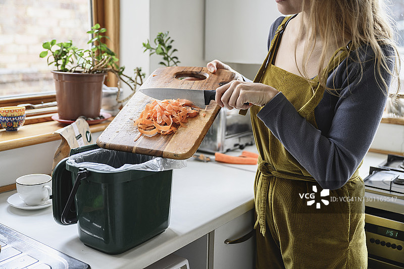 中年妇女将胡萝卜屑放入堆肥箱图片素材