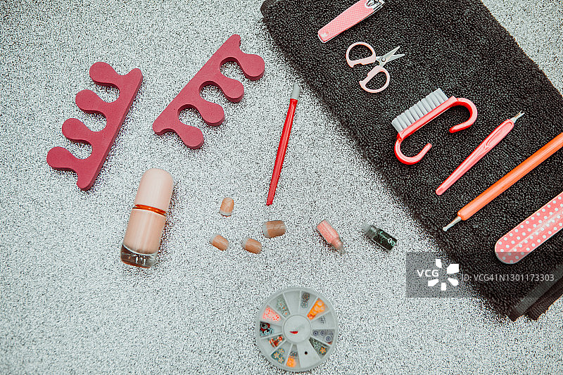 美甲套装和黑色毛巾在粉彩灰色桌子上，文字或LOGO的空位，特写，平放，俯视图片素材
