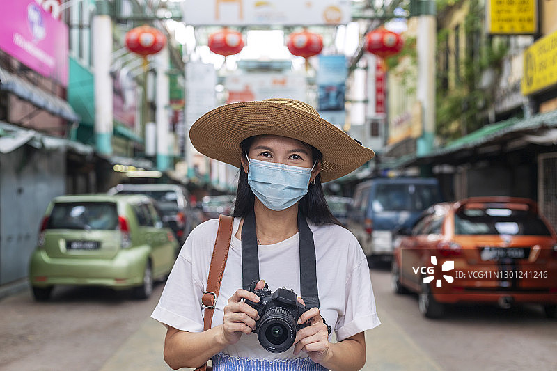 快乐的年轻亚洲女性在城市街道上戴着面膜图片素材