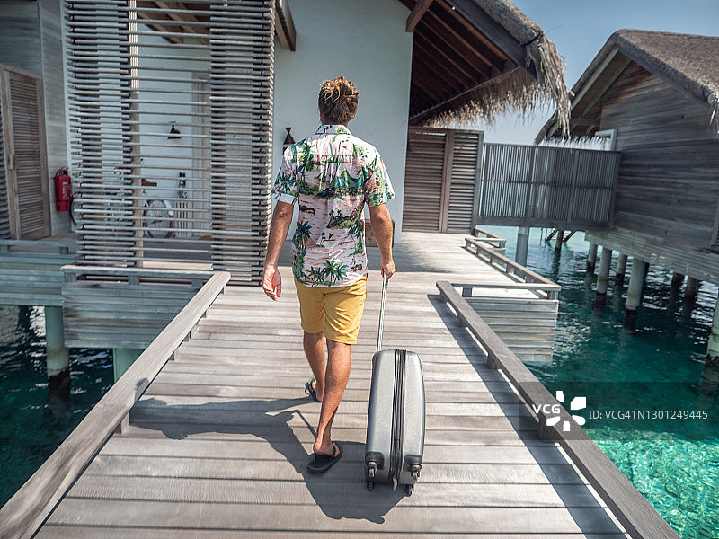 男人在热带目的地的木制码头上拉手推车图片素材