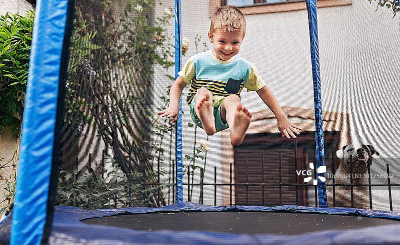 在蹦床上跳跃的快乐小男孩图片素材