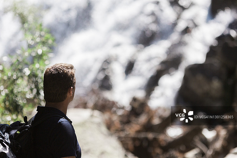 中年男人在阳光明媚的日子里在山路上徒步旅行图片素材