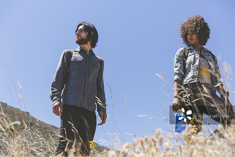 仰视站在蓝天下的年轻情侣图片素材