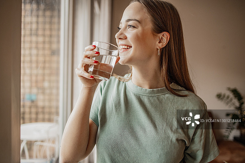 年轻女人在窗边喝水图片素材