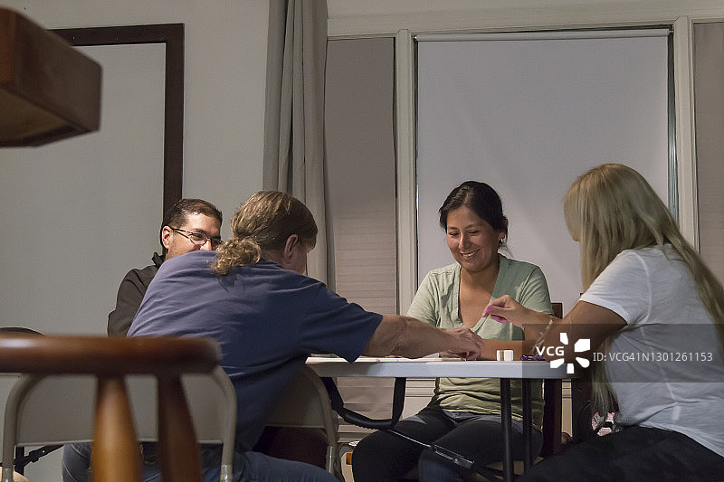 多代多种族美籍/拉丁家庭周六晚上在家玩多米诺骨牌图片素材