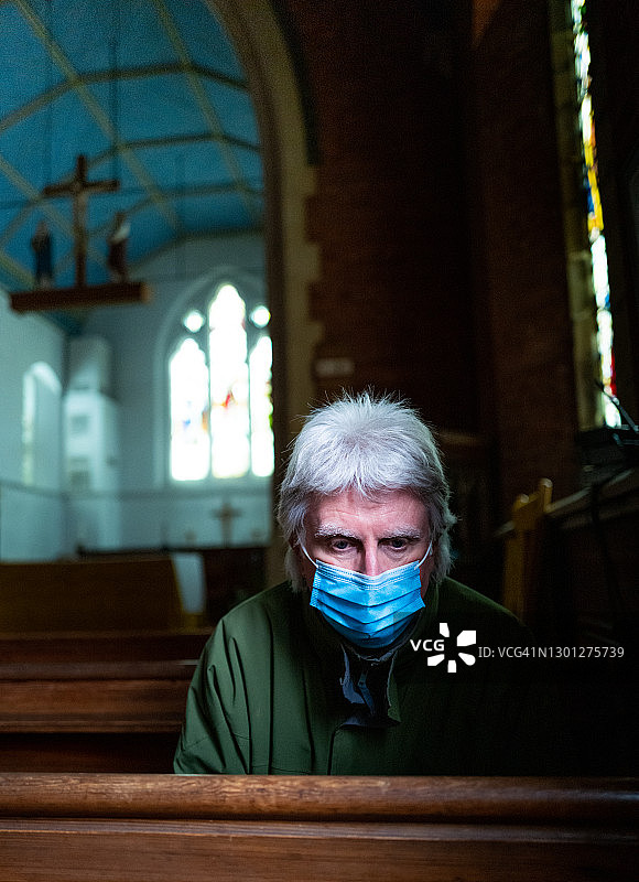 在教堂内戴口罩祈祷的年长男人图片素材
