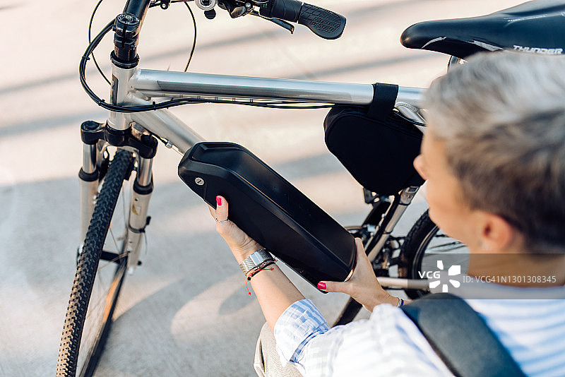 在街上更换电动自行车电池的女人图片素材