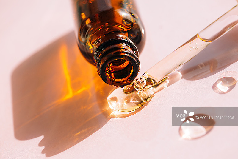 粉色背景上滴落的面部精华液图片素材