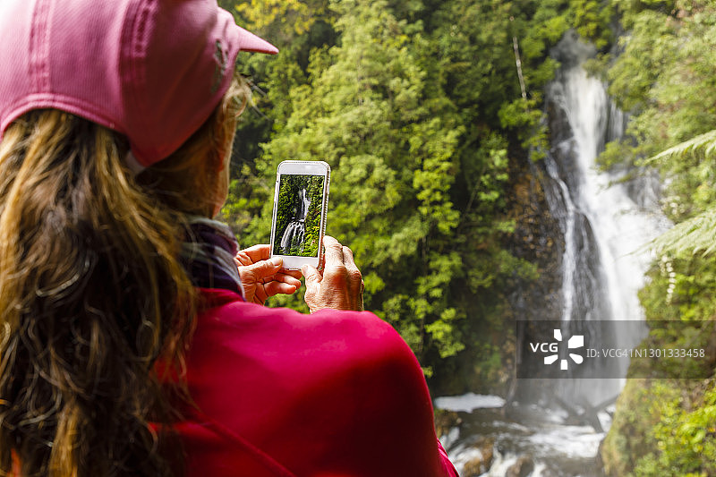 女人用手机拍摄哲学家瀑布图片素材