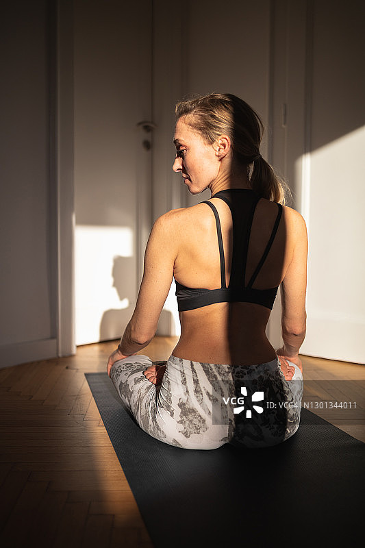在家中运动垫上呈莲花坐姿的女子背影图片素材