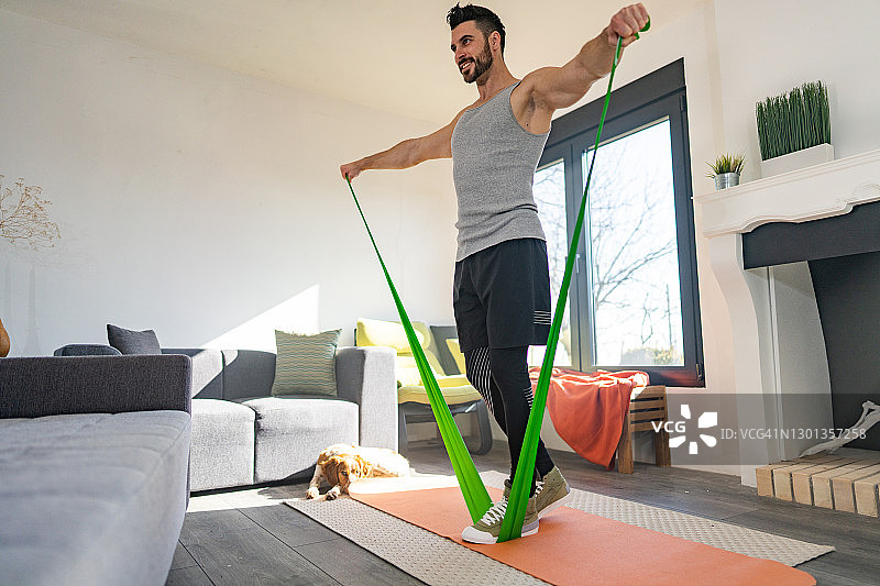 男运动员在客厅用弹力带锻炼图片素材