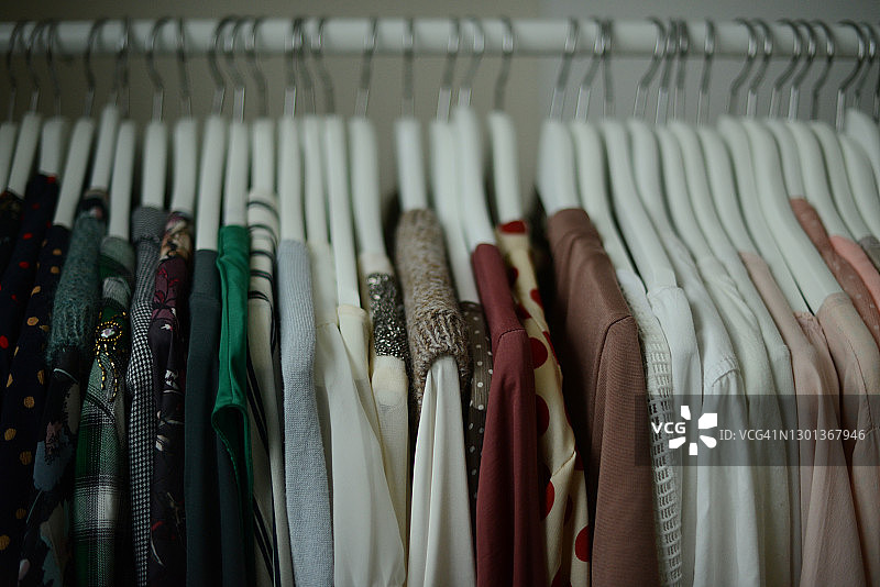 按颜色排列的白色衣架上不同颜色的女式衬衫图片素材