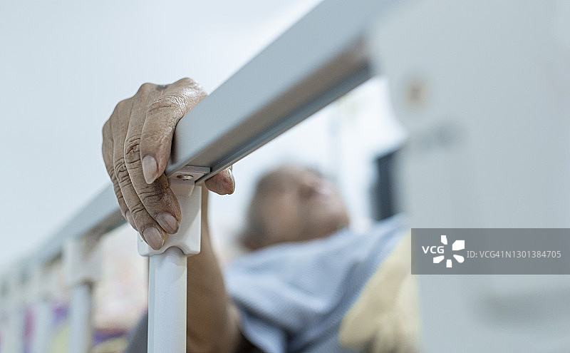 带气管造口管的亚洲老人躺在床上看摄像头视频通话图片素材