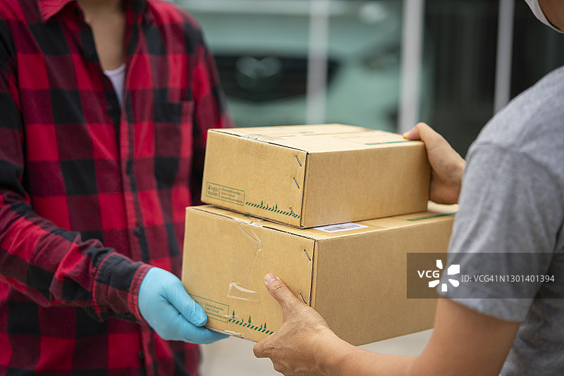送货员在家中给年轻男子送盒子的中段照片图片素材