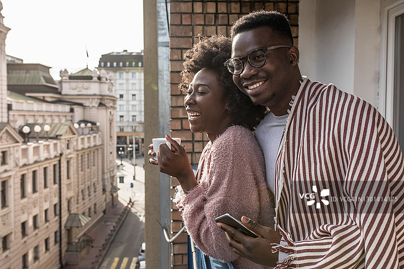年轻情侣在阳台上享受阳光明媚的一天图片素材