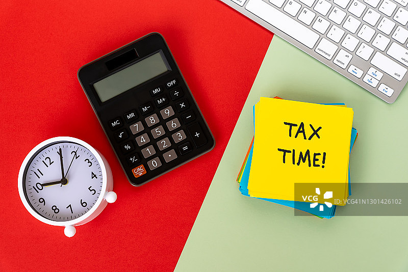 红色和绿色背景上的税务申报通知，计算器，电脑键盘和闹钟图片素材