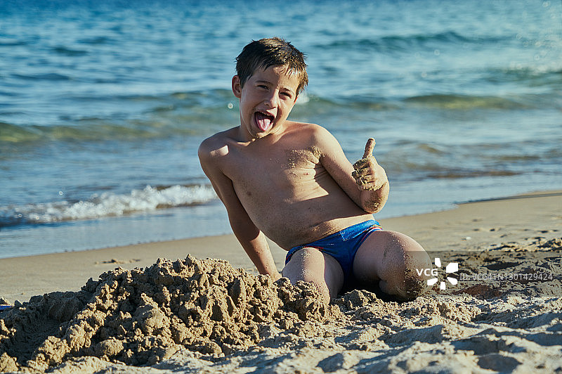 在海滩玩沙子的小男孩图片素材