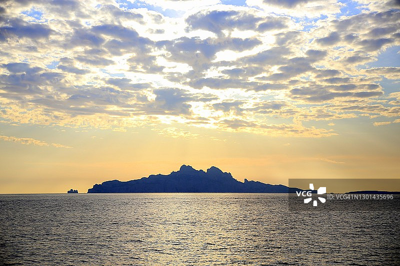 夕阳下多云蓝天下，海中岛屿的轮廓图片素材