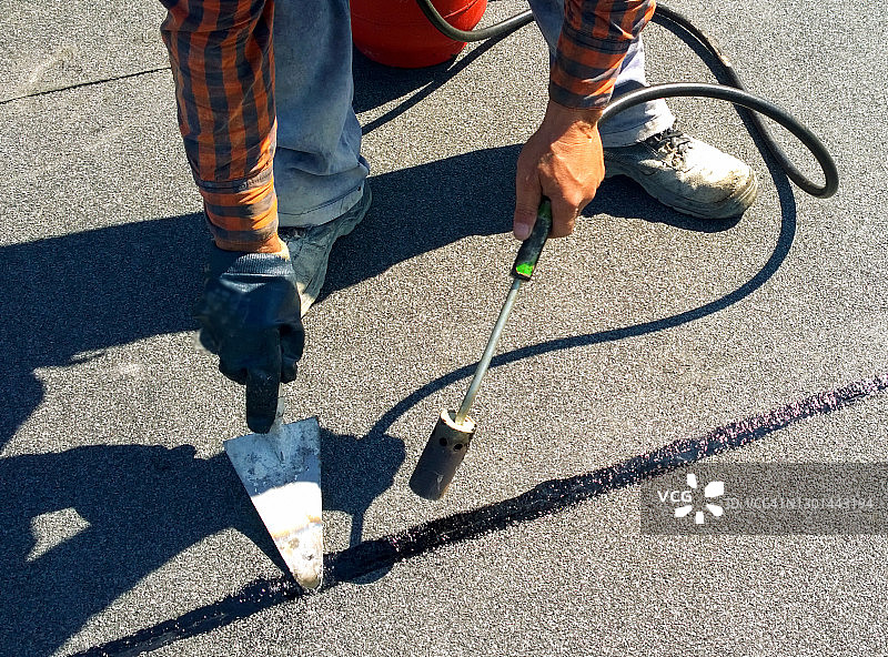 屋顶工准备用燃气加热器喷枪融化沥青屋顶毡卷图片素材