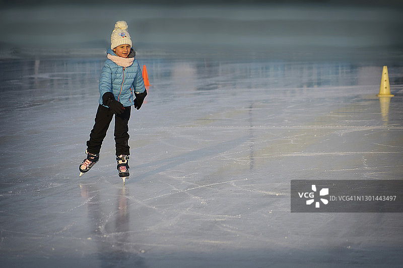 穿着溜冰鞋在冰上保持平衡的年轻女孩图片素材