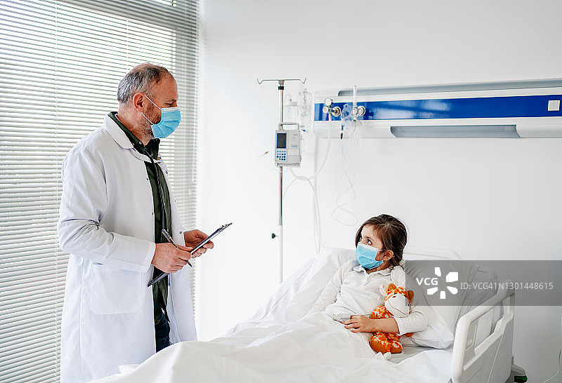 戴着防护口罩躺在医院病床上的生病儿童图片素材