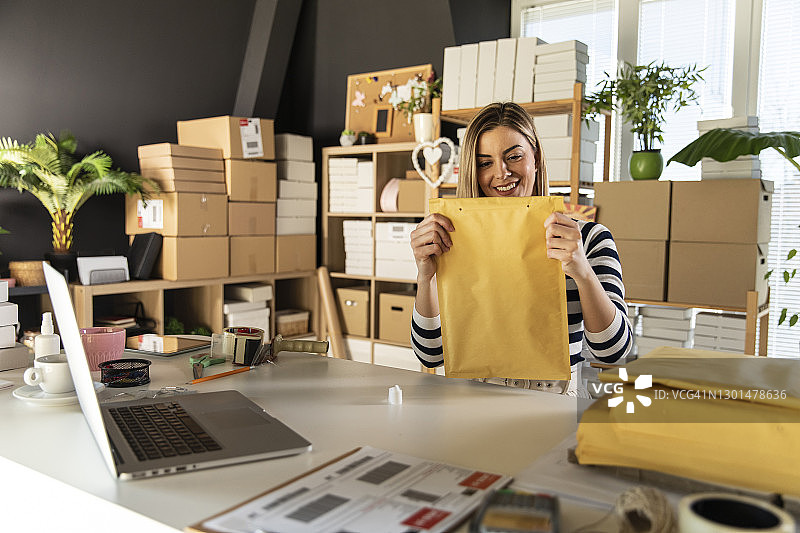 微笑的年轻女企业家在黄色信封中包装订单图片素材