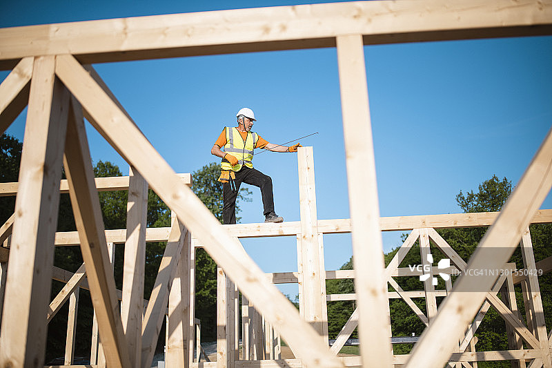 在木屋顶上工作的年长建筑工人。图片素材