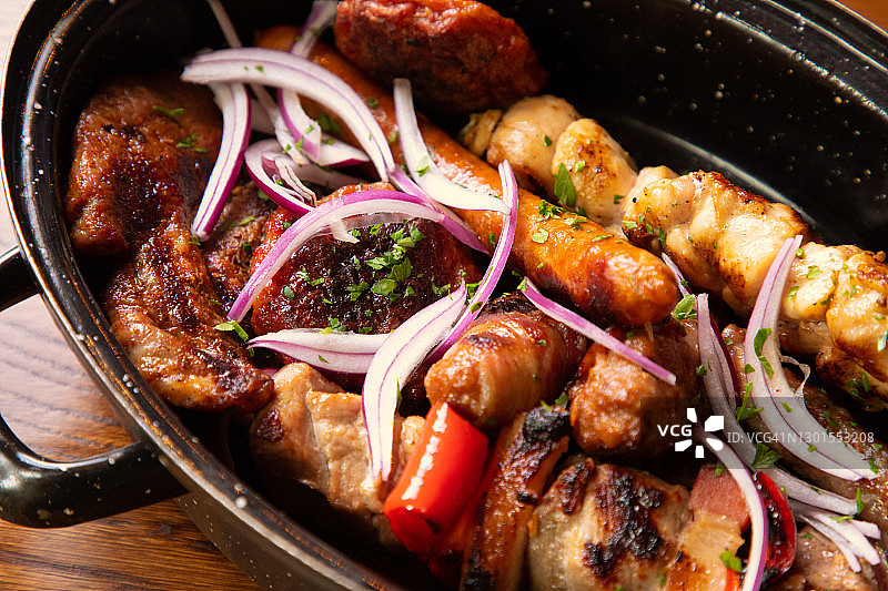 深盘中盛放的各种烤肉，用洋葱片和欧芹调味图片素材