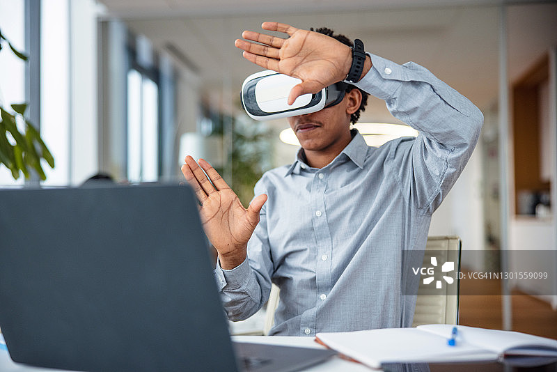 在办公室与虚拟现实头显互动的商务人士图片素材