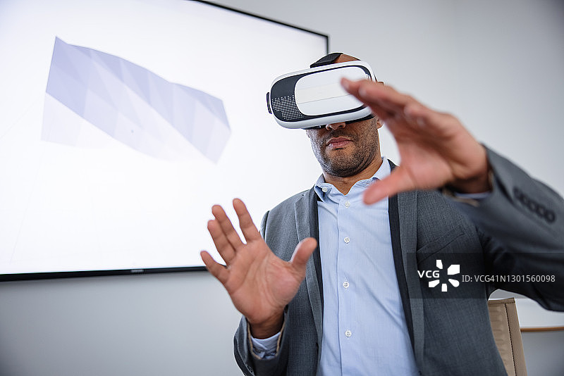 商务男士在虚拟现实头显中与3D模型互动图片素材