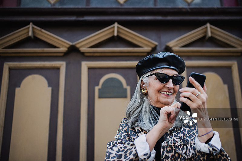 在城镇户外穿着奢华服装，使用智能手机的年长女性图片素材