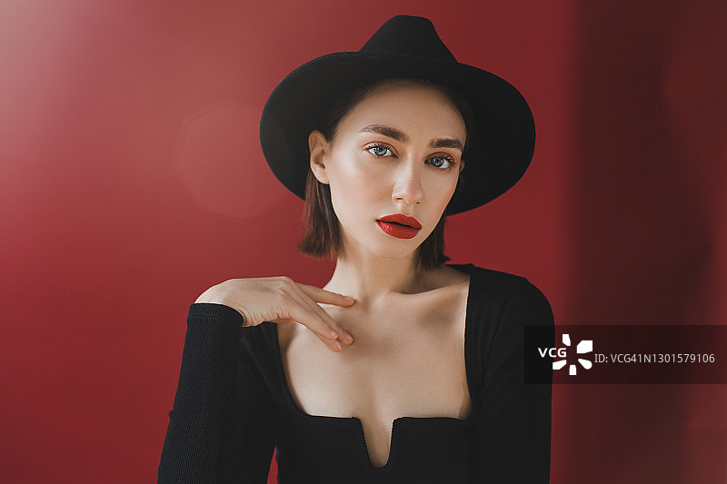 红底上化着鲜艳妆容、戴帽子的美丽女孩肖像图片素材