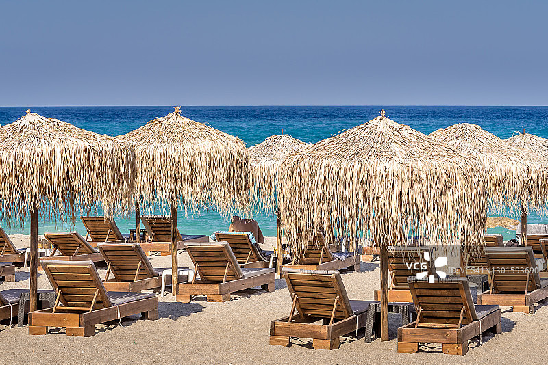 希腊爱琴海玛格尼西亚佩利翁半岛Agioi Saranda海滩的风景，有茅草伞和沙滩椅图片素材