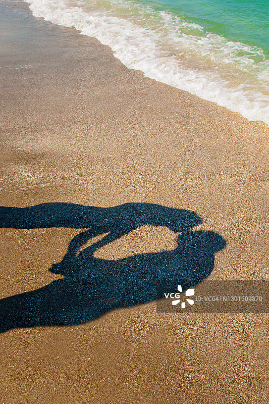 情侣在沙滩上亲吻牵手，海面的阴影图片素材