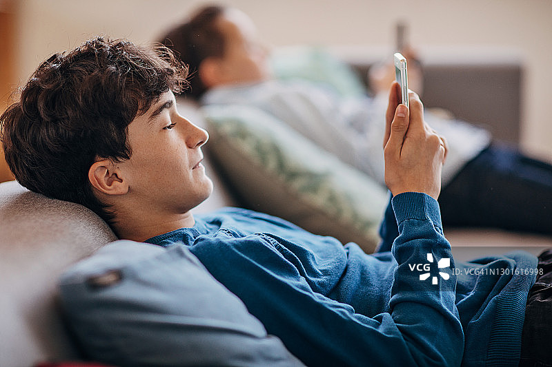 男孩们在家使用智能手机图片素材