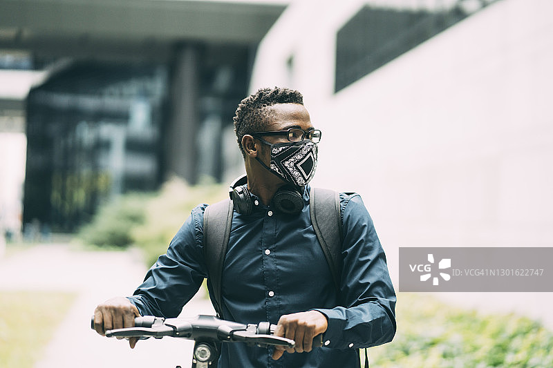 戴口罩的黑人男人骑踏板车图片素材