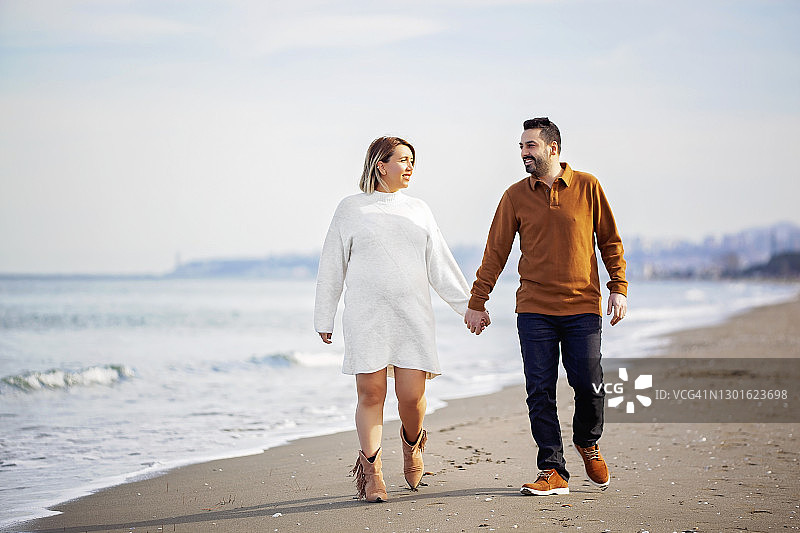孕妇和丈夫在海滩上散步图片素材